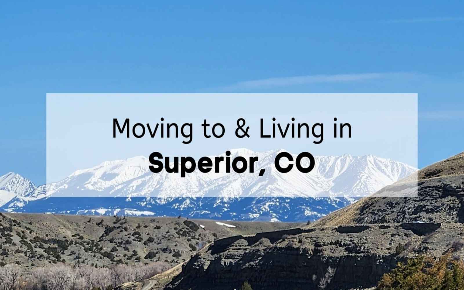A panoramic scenic view of snow-capped Rocky Mountain peaks under a clear blue sky, capturing the landscape surrounding Superior Colorado, overlaid with a white translucent banner reading 'Moving to & Living in Superior, CO'.
