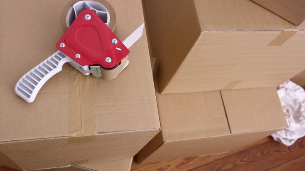 Professionally packed moving boxes stacked on top of each other with a tape gun on top.